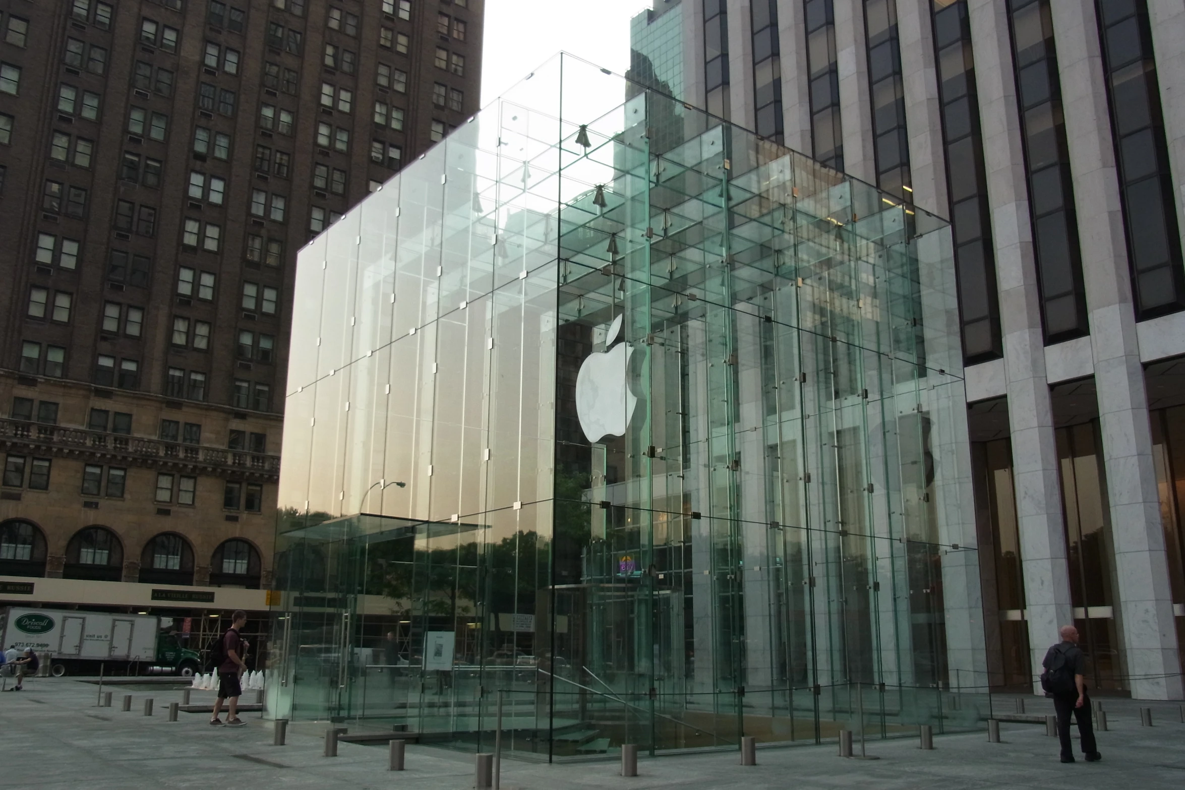 a glass structure next to a tall building in an urban area