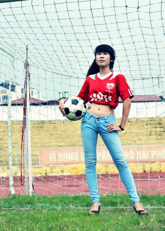 woman posing in a soccer field with a ball