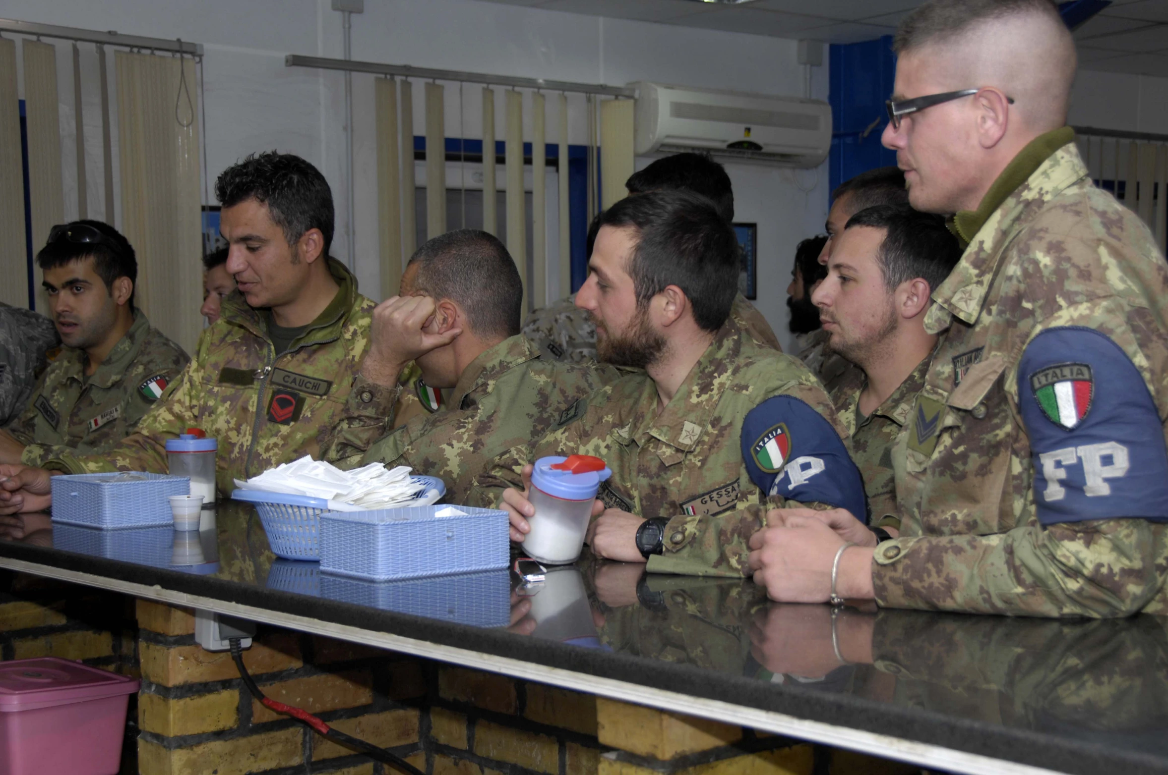 soldiers sitting at a table eating from containers