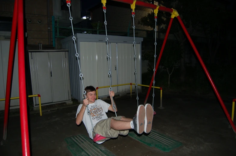 a little boy is on a swing near the building