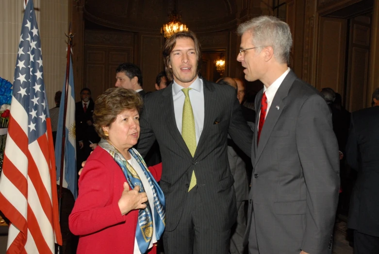 three well dressed men standing next to each other talking