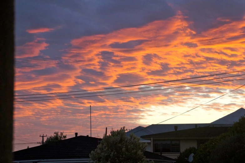 the sky above houses and telephone poles on the side of the road