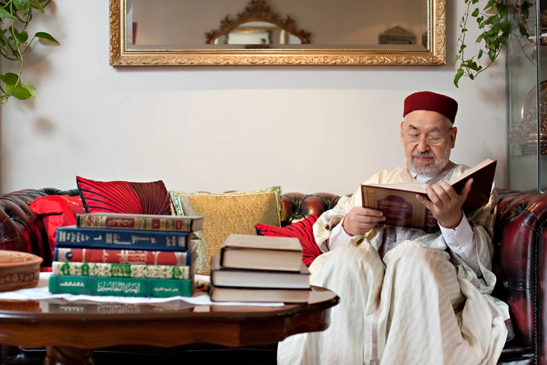 a man sitting on top of a couch holding a book