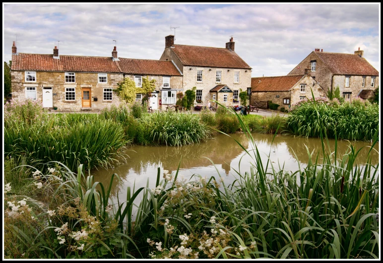 a river runs through a rural area by some houses