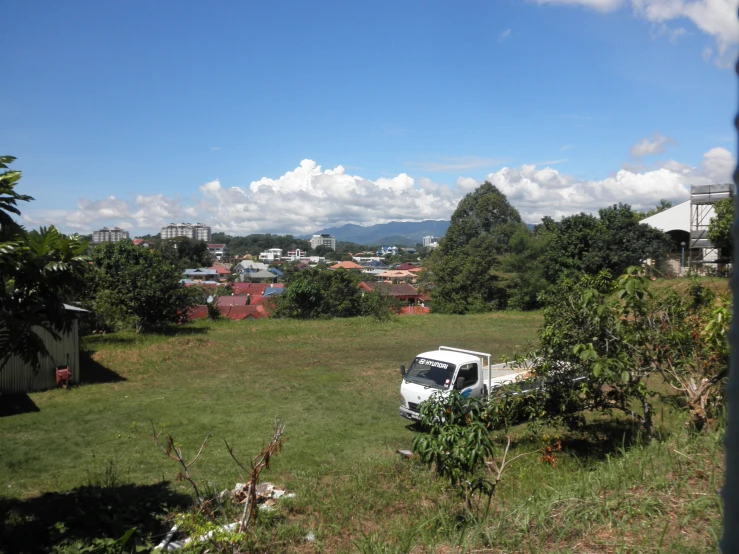 a delivery truck parked in a field with lots of trees and mountains in the background