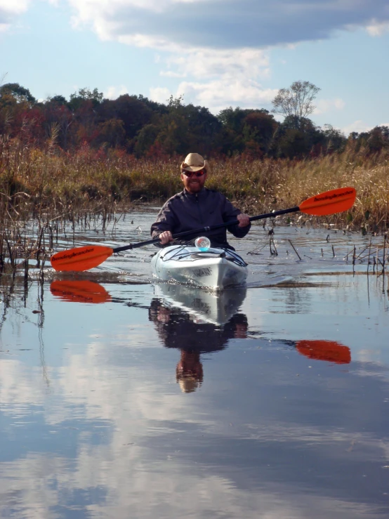 a man with a hat on paddles his canoe through water