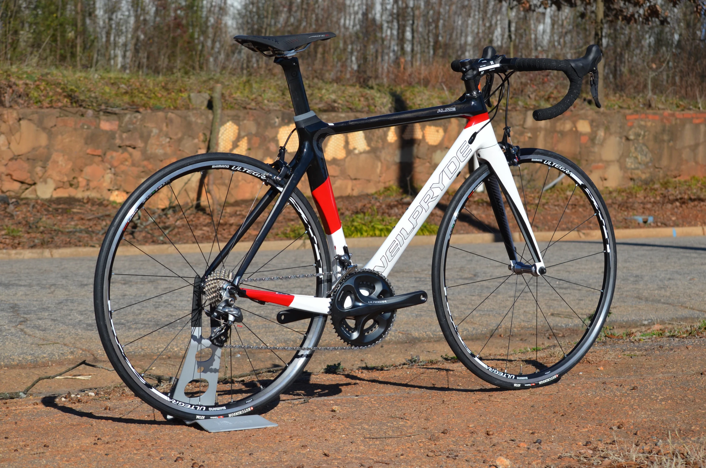 a white bicycle is leaning against a pole on the road