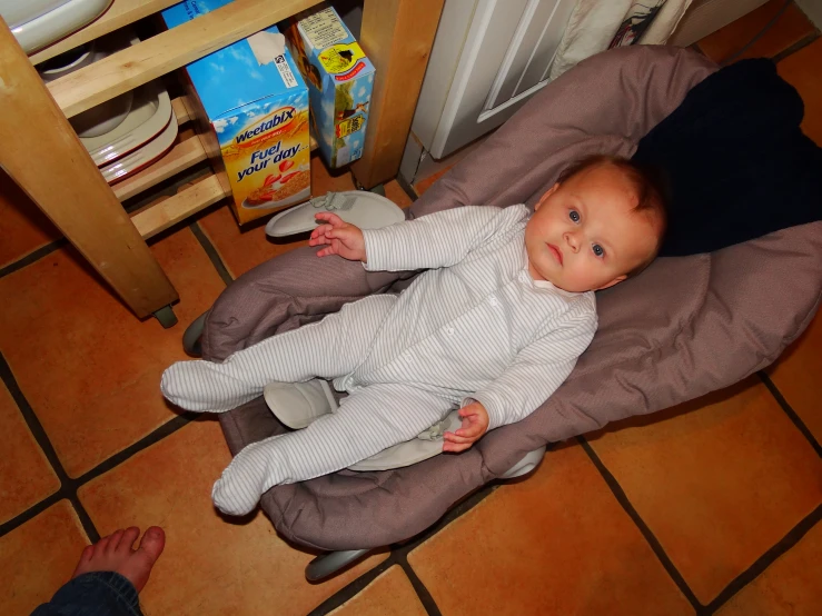 a baby laying down on a brown chair