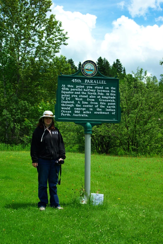 woman standing in front of a marker sign on top of a lush green field