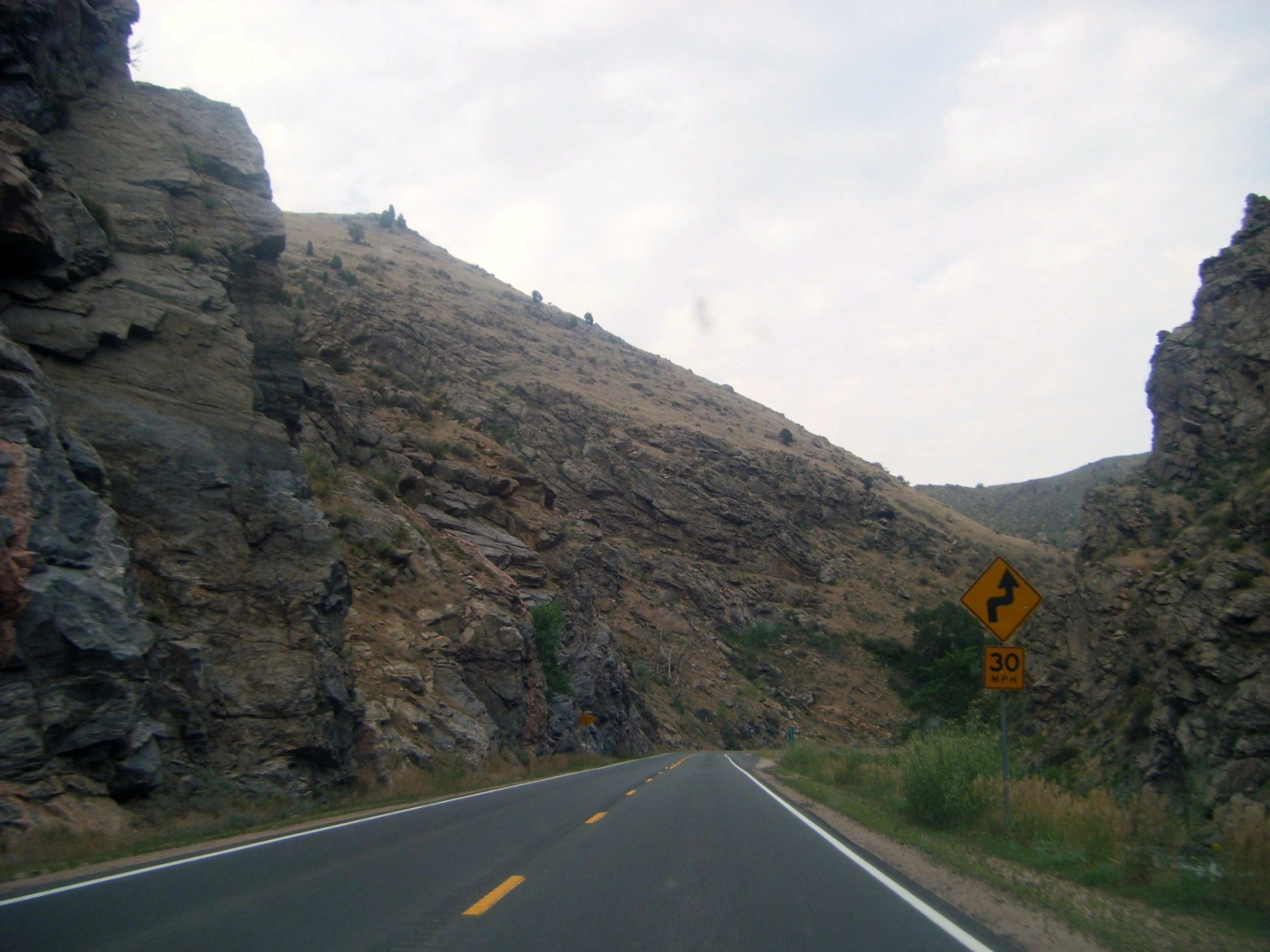 a street sign and a cliff on the side of a road