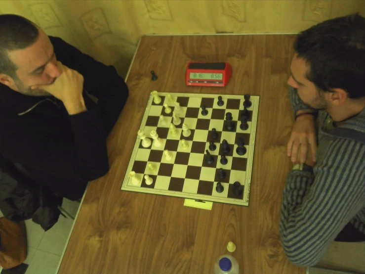 two men sit at a table playing checkers