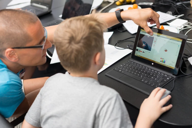 man and boy looking at electronic device in classroom