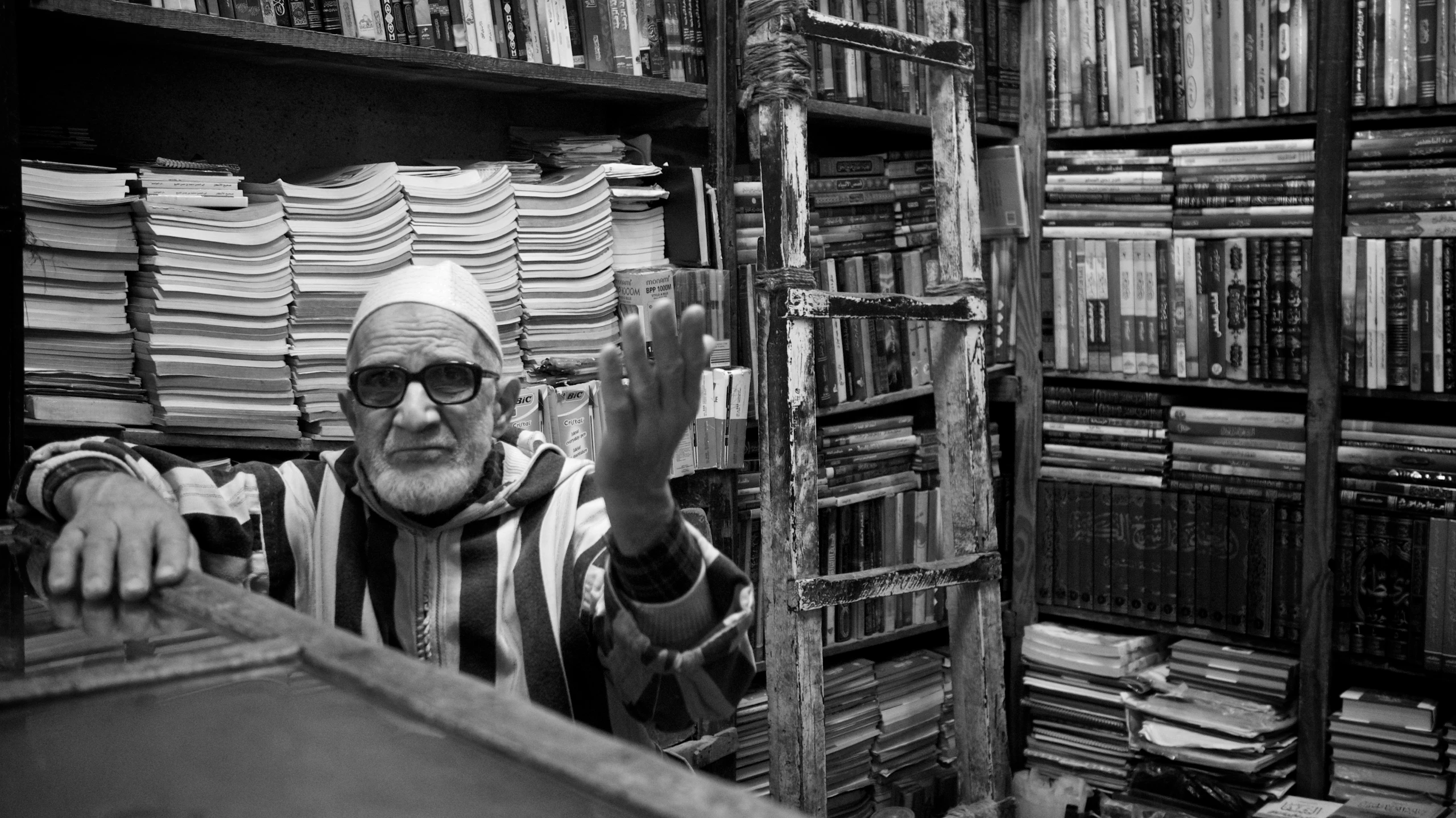 a man in a striped robe leaning on shelves filled with books