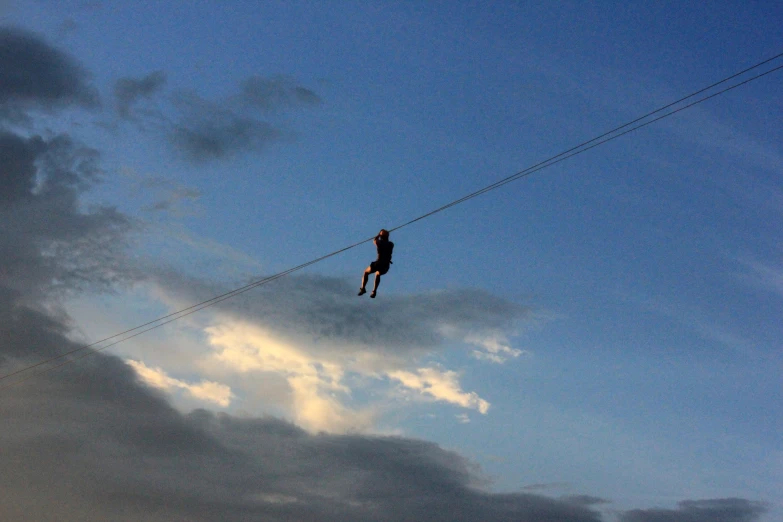 a man hanging from a rope on a cloudy day