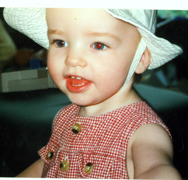 a small child with big red eyes wearing a hat