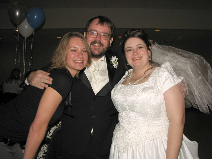 three people dressed up for wedding posing for a picture