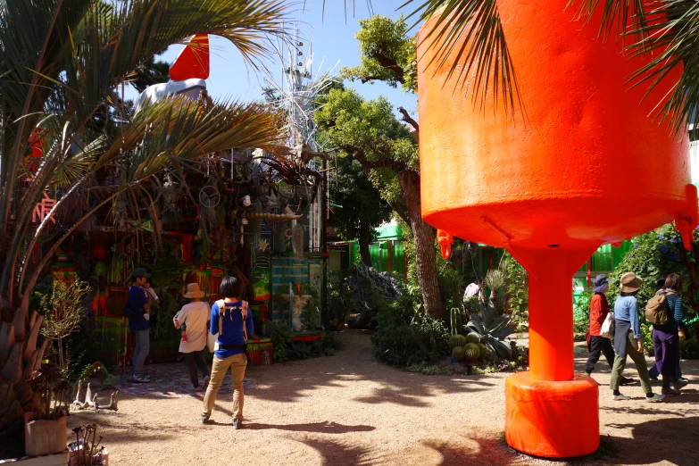 several people looking at plants and statues that look like giant orange cylinders