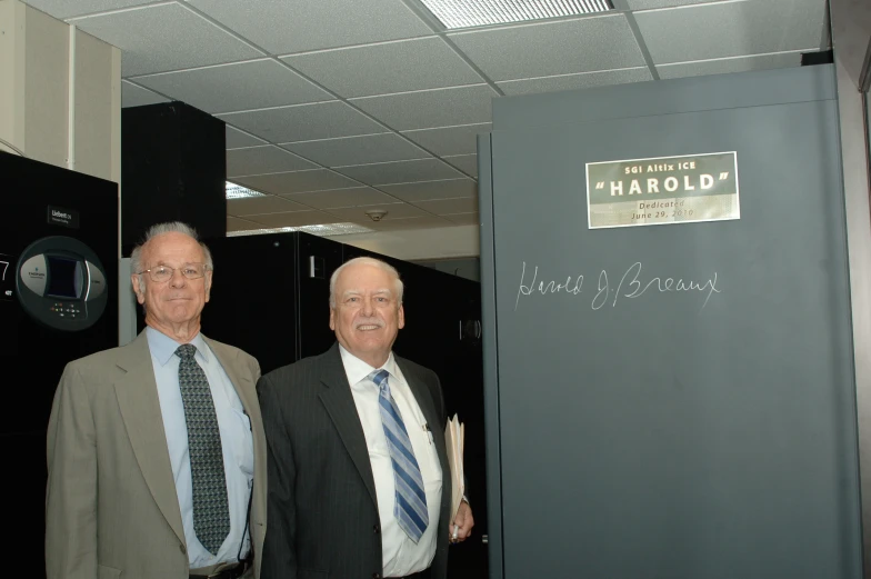 two men stand next to each other in suits and ties