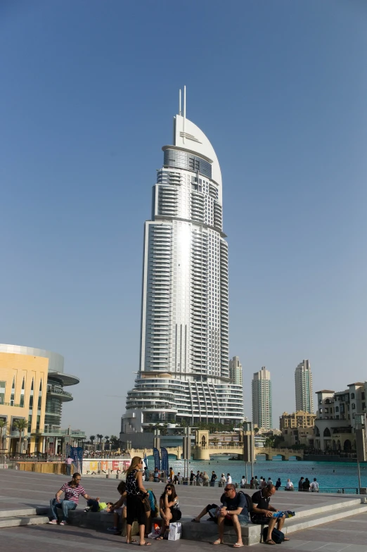 several people are sitting on benches outside in front of a tall building