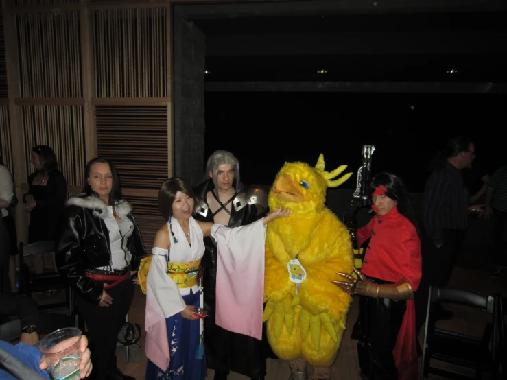 four people are posing with a yellow mascot