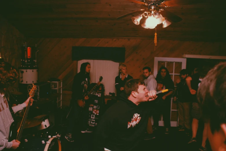 two men sing while playing guitars and bass in front of an audience