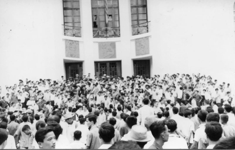 an old picture of people sitting at a big building