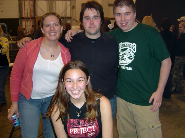 the four people are standing together in front of a large crowd