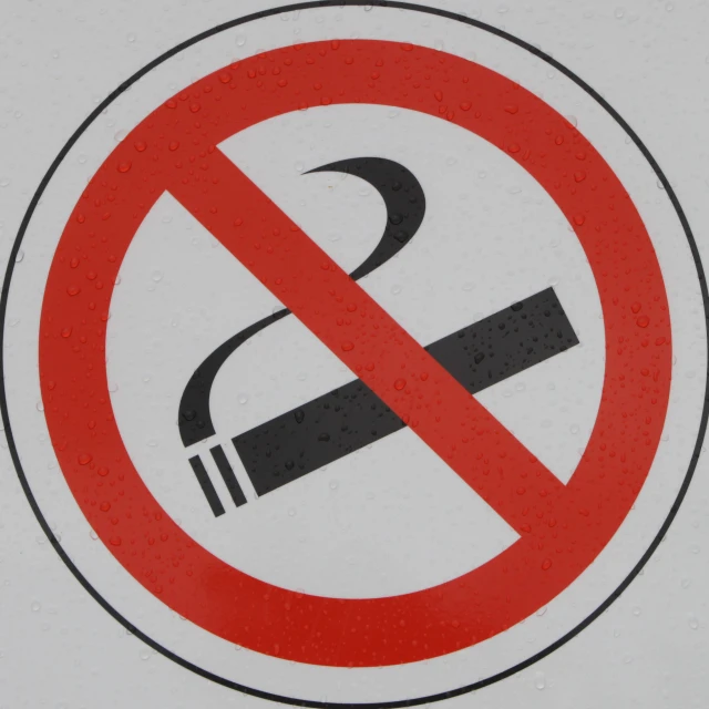 a red and white sign with black smoke in it