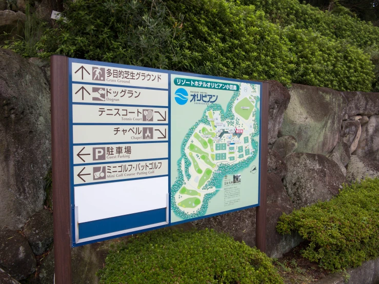 a sign posted in front of a rock wall