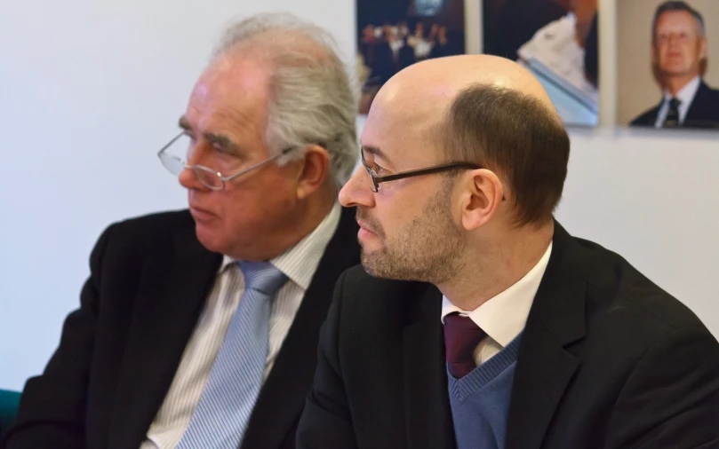 two men sitting next to each other during a meeting