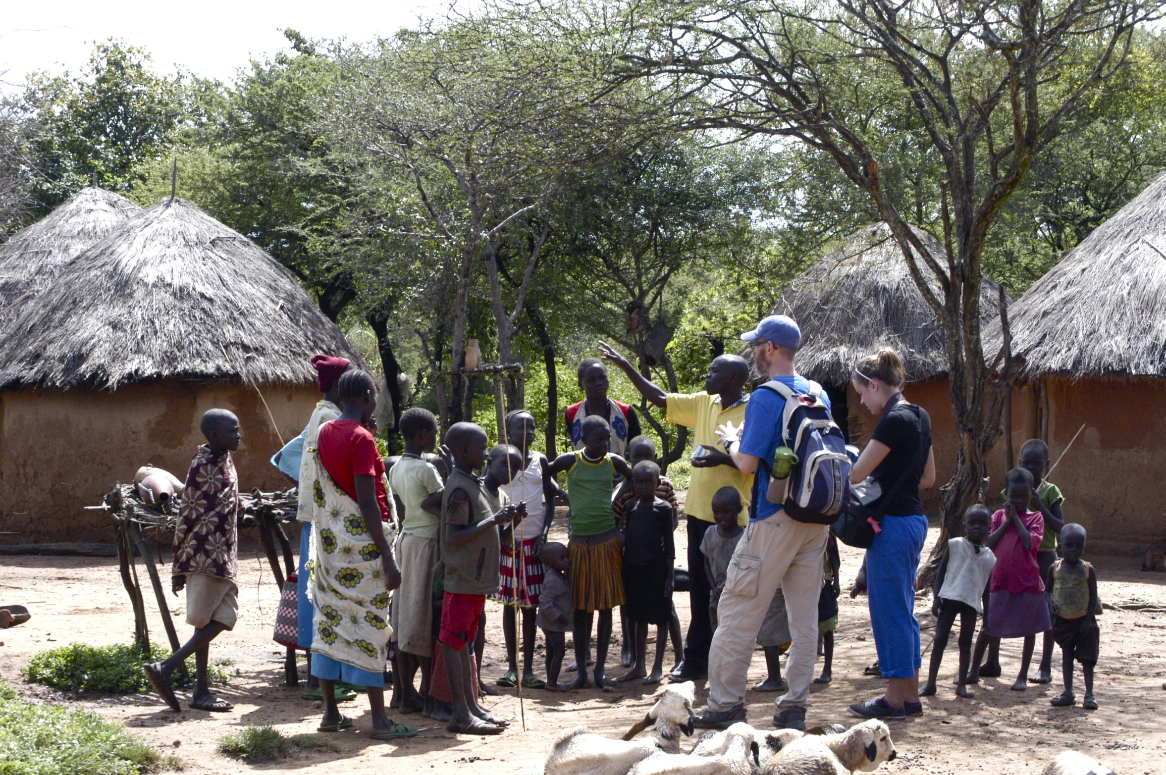 group of children standing in front of small huts