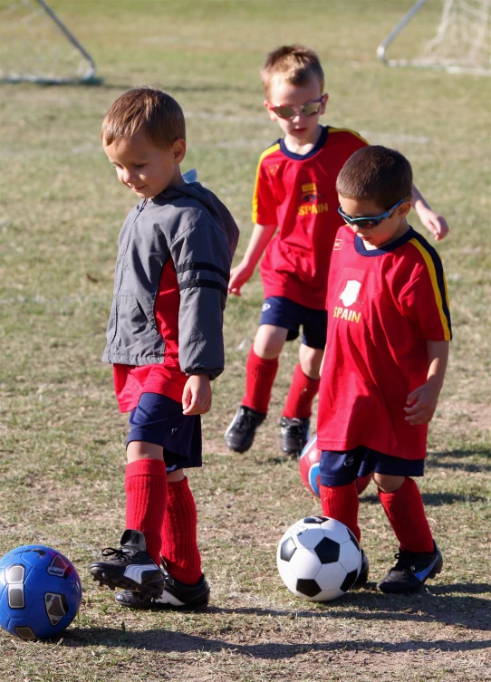 three s in uniforms playing soccer