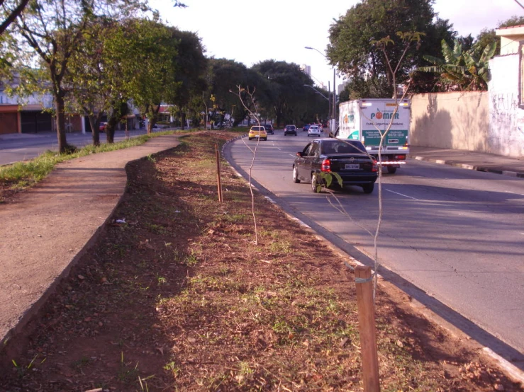 a line of poles along a road that contains a street name, and two markers with cars driving on it