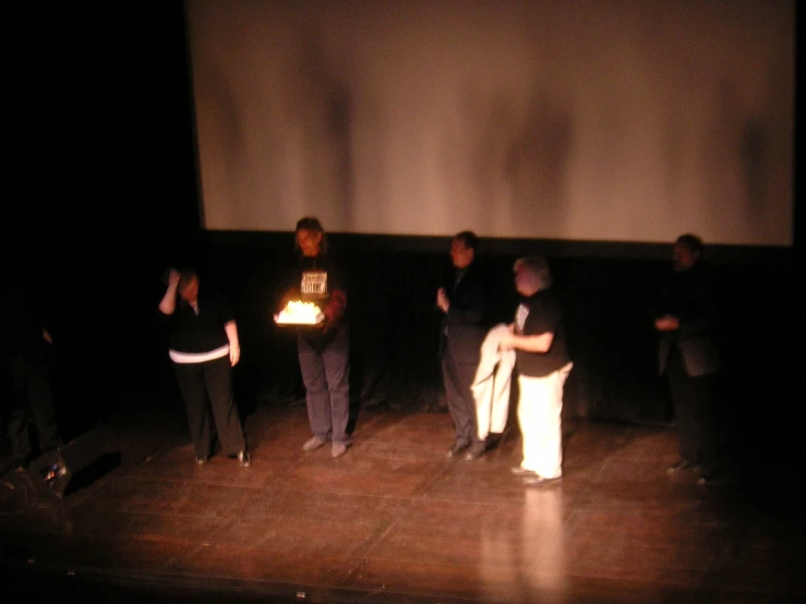 some people are standing on a stage while one man is holding a light