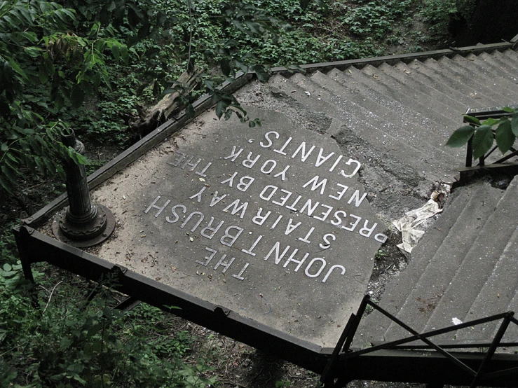 an old writing on a building surrounded by vegetation