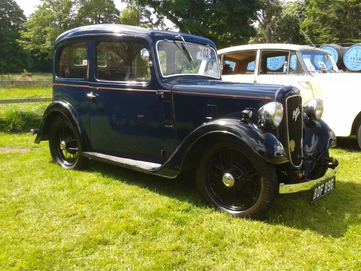 a couple of old fashioned cars that are in the grass