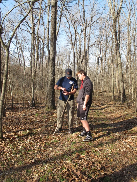 two men standing in a forest with woods in the background