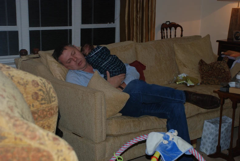 a man is sleeping on a couch while his dog sits on the sofa