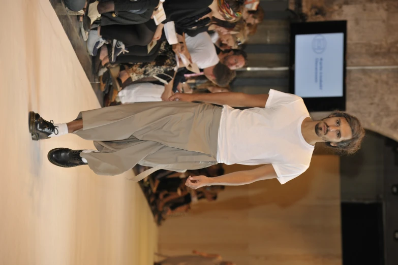 a man wearing white shirt and khaki pants walks down the runway