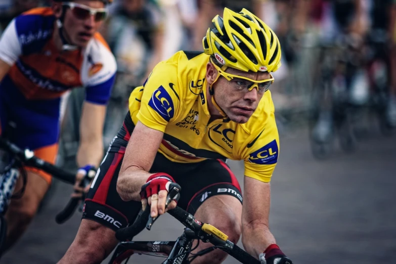 a cyclist in a yellow jersey and red socks is next to another bicyclist