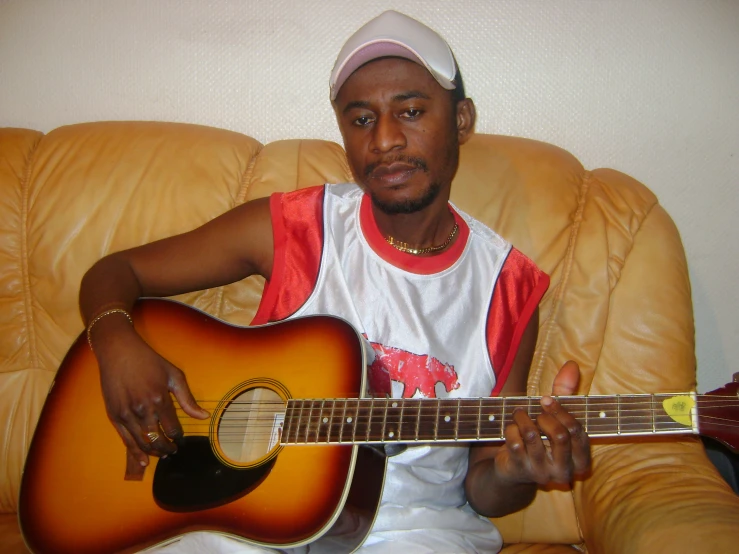 a man is sitting on a couch with a guitar