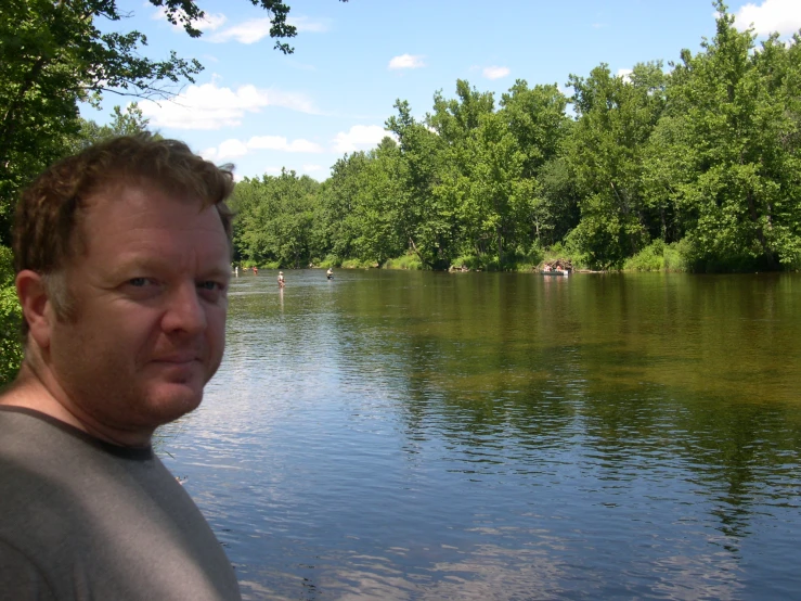 a man poses for a picture next to a lake