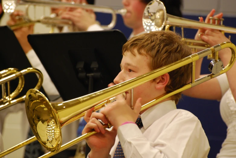 a  holding a trumpet to his ear while other people play music behind him