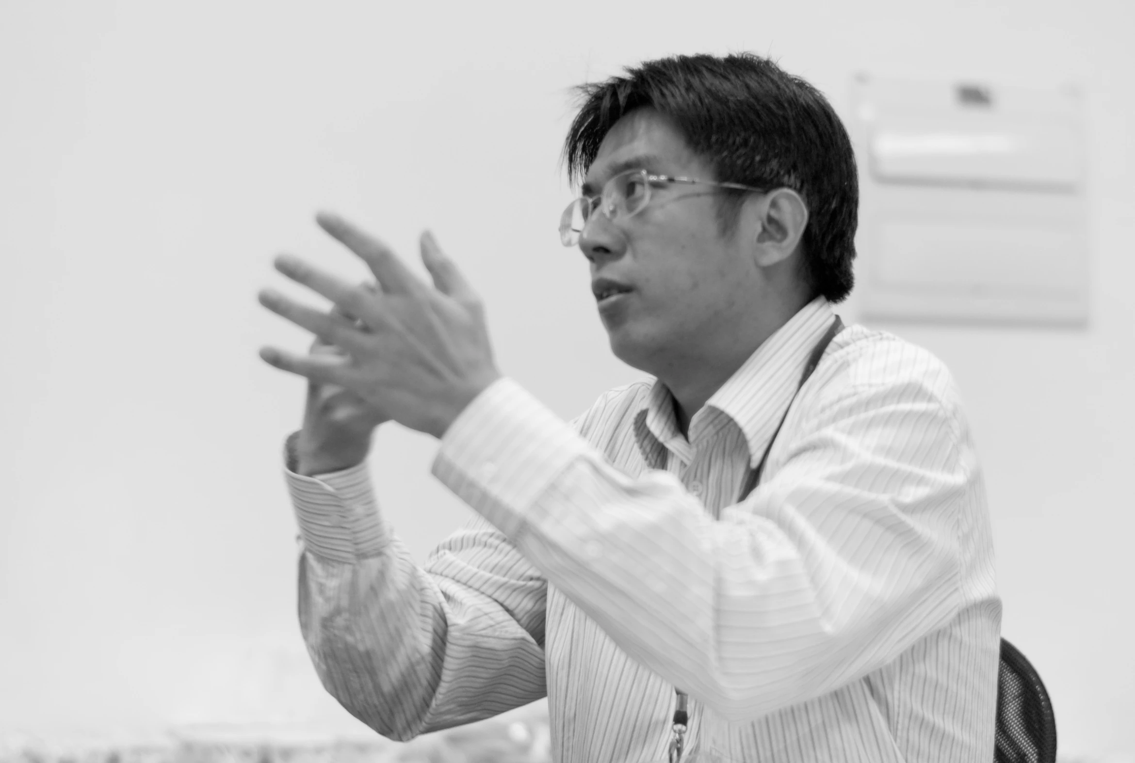 a black and white image of a man with glasses gesturing