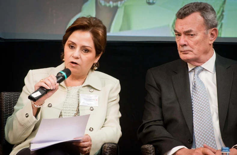 a man and woman in business attire sitting at a microphone