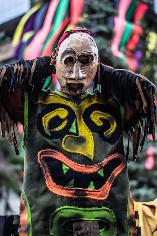 a painted mask hangs in the street with other colorful flags