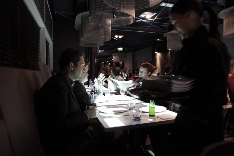 several people sitting at a restaurant table with white linens