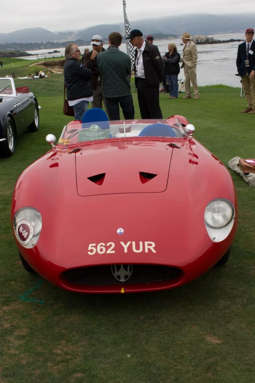 some people and an old style sports car