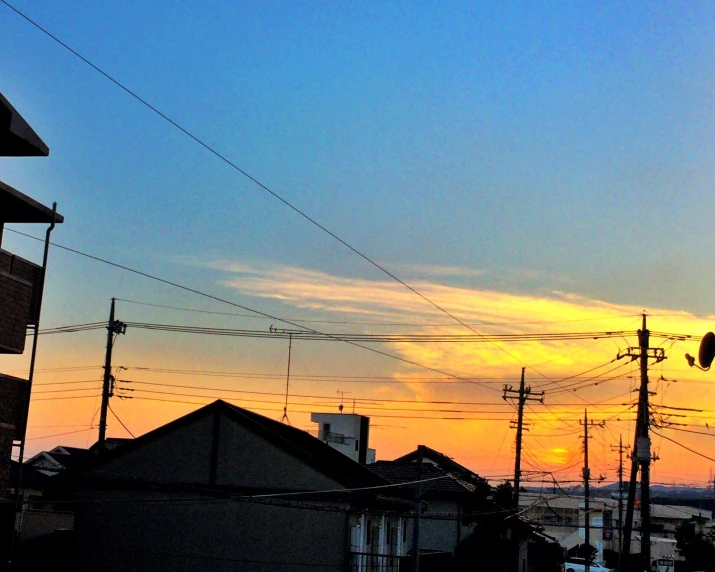 a colorful sun sets in the background behind a small city