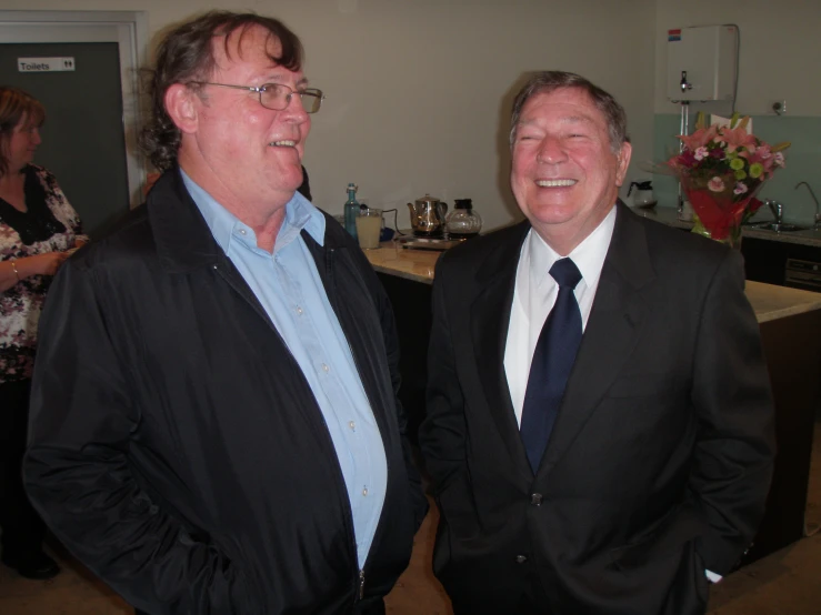 two men are standing in a room talking